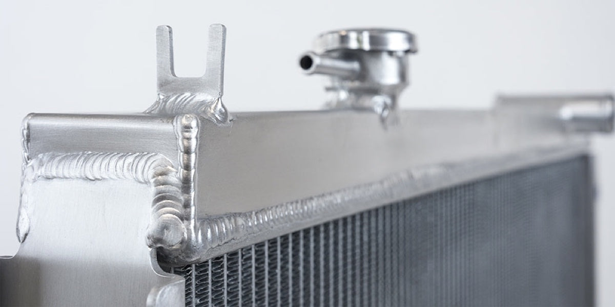 Close-up of a radiator tank, mounting point and finned core.
